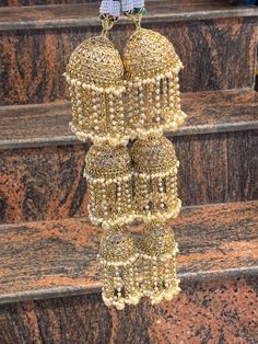 two bells hanging from the side of some steps with beads on them and beading around it