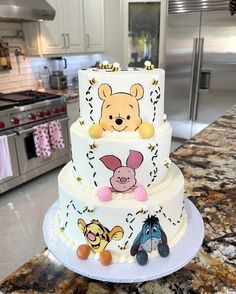 a three tiered winnie the pooh cake on top of a marble countertop