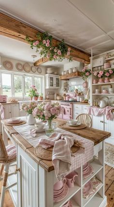 a kitchen filled with lots of pink flowers and dishes on top of a wooden table