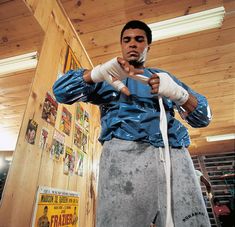 a man with bandages on his hands standing in front of a wooden wall