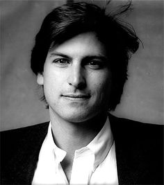 a black and white photo of a man in a suit with his hair pulled back