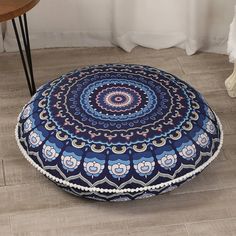 a blue and white round floor pillow on the floor next to a table with a chair