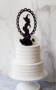 a white cake topped with a silhouette of a witch