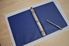 a blue binder with a pen sitting on top of it