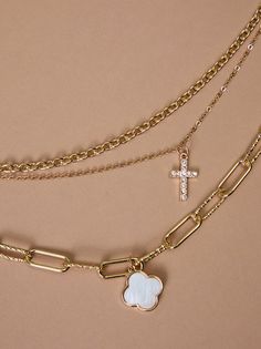 Faith and fashion meet in this layered necklace. Three delicate chains showcase a shimmering mother-of-pearl clover, a golden cross, and sparkling crystals, offering a statement piece for any occasion. Golden Cross, Cross Necklaces, Floral Shop, A Cross, Accessories Jewelry Necklace, Mini Dress Shop, Altar'd State, Layered Necklace, Sparkling Crystal