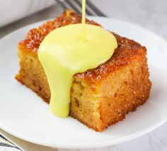 a piece of cake on a white plate with a yellow sauce drizzled over it