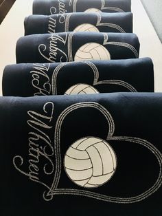 four towels with embroidered volleyballs on them are lined up in a row and one has a heart