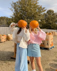 two young women holding pumpkins on their heads