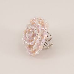 a pink and white beaded ring sitting on top of a table