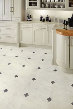 a kitchen with white cabinets and black and white floor tiles on the floor, along with an island in the middle