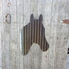 a metal horse head on the side of a wooden fence next to a rusted door