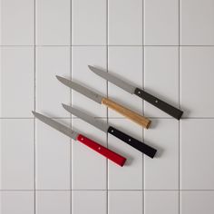 three knives on a white tile background