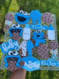 someone holding up some cookie cookies with blue icing on them and the words it's a boy