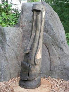 a large wooden sculpture sitting on top of a pile of wood next to some rocks