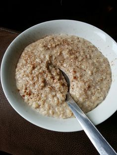 a bowl of oatmeal with a spoon in it on a brown table