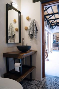 a bathroom sink sitting under a mirror next to a white toilet and wooden counter top