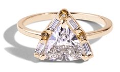 a yellow gold ring with a pear shaped diamond and baguets on the side