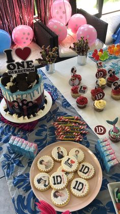 a table topped with cakes and cupcakes on top of a table covered in balloons