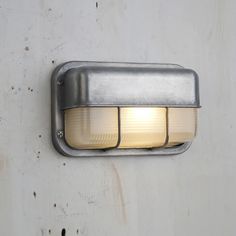 a wall mounted light on the side of a building with rusted metal and white paint