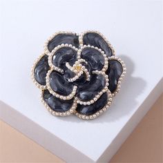 This intriguing brooch features a floral motif and is outlined in shining pearl detail. 1.65" W x 1.65" L 18k gold-plated copper / enamel / pearl Pearls Fashion, Camellia Flower, Scarf Hat, Fashion Costume, Black Pearl, Comfortable Dress, Safety Pin, Flower Brooch, Backpack Purse