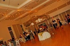 a group of people standing around in a room with lights on the ceiling and tables