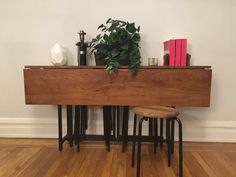 a wooden table sitting on top of a hard wood floor next to two stools