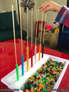 a cake with candy sticks sticking out of it on a red table in front of a child's hand