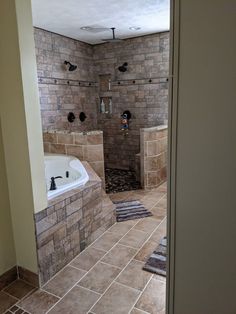 a large bathroom with a walk in shower next to a white bath tub and tiled floor