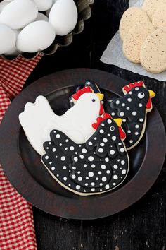 two decorated cookies on a plate next to eggs