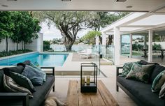 a living room filled with furniture and a swimming pool in the backround next to it