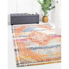 an orange and blue area rug in a living room with a couch, potted plant and