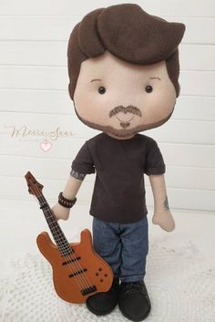 a stuffed toy is holding a guitar and wearing a brown t - shirt with a mustache