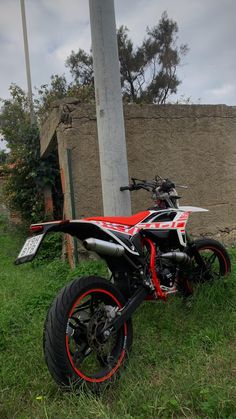 a red and white dirt bike parked in the grass