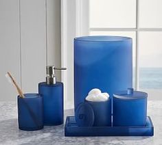 a blue bathroom set with soap dispenser and toothbrush holder