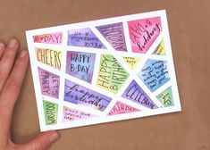 someone is holding up a card with happy birthday written on it in different colors and shapes