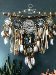 a wall hanging with dream catchers, lights and plants on it's side