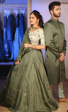 a man and woman standing next to each other in front of a rack of dresses