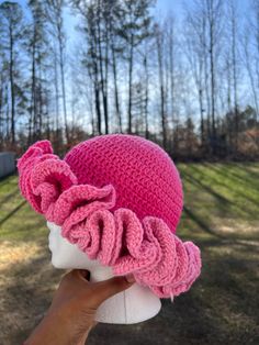 a woman's hand holding up a pink knitted hat