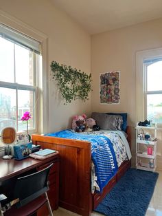 a bed room with a neatly made bed next to two windows and a blue rug on the floor