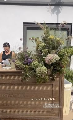 a woman standing behind a wooden counter with flowers on it