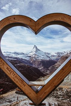 a wooden heart shaped frame on top of a mountain