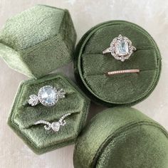 four green velvet jewelry cases with diamond rings in them