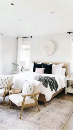 a white bedroom with black and white accessories on the bed, rugs and windows