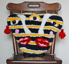 a stuffed animal is sitting on top of a wooden chair with pom poms