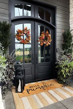 the front door is decorated with fall wreaths and welcome mats for guests to enter