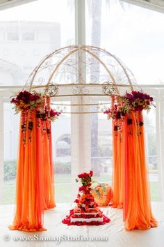 an orange and white wedding setup with flowers on the top, draped draping