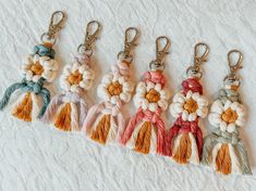 six tasseled keychains with flowers on them sitting on a white surface