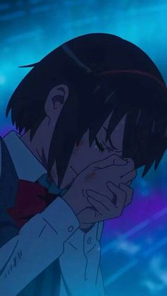 an anime character holding his hand to his face and looking into the distance with blue lights behind him