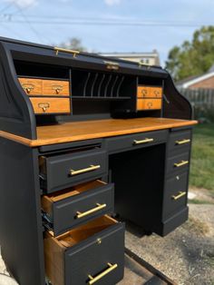 an old fashioned desk with drawers on the bottom and gold handles, sits outside in front of a house