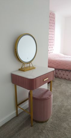 a dressing table with a mirror and stool in a small room next to a bed